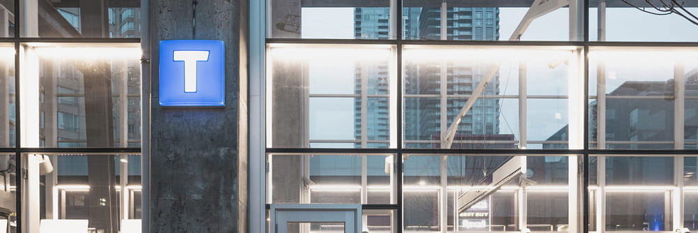 The TransLink T sign illuminated at a SkyTrain station