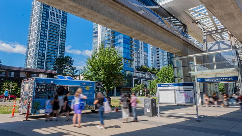 A Chickpea food truck parked outside Metrotown Station in Burnaby on a sunny day, with people lined up to order