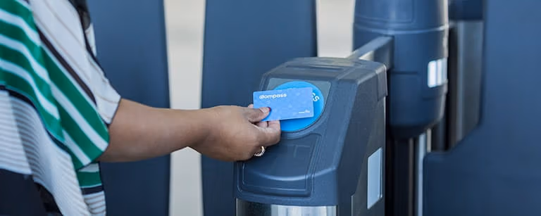 A person tapping their Compass card to open the fare gate