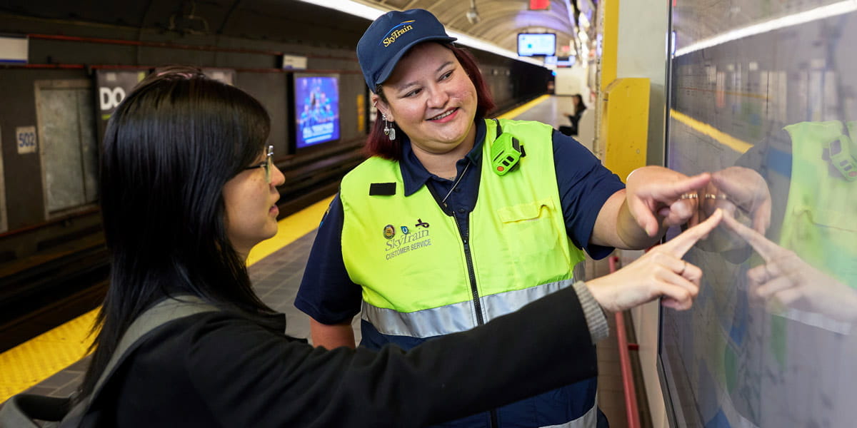 SkyTrain attendant helping customer with system map in station