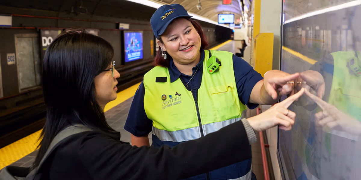 SkyTrain attendant helping customer with system map in station