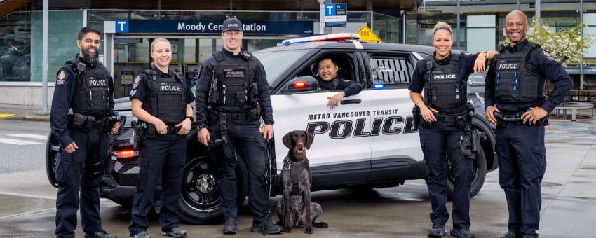 Transit police officers standing by the police car in front of Moody Centre Station
