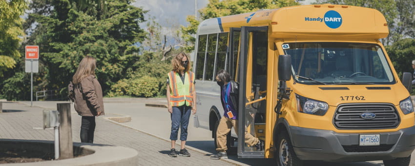 HandyDART driver assisting an elderly passenger with exiting the bus.