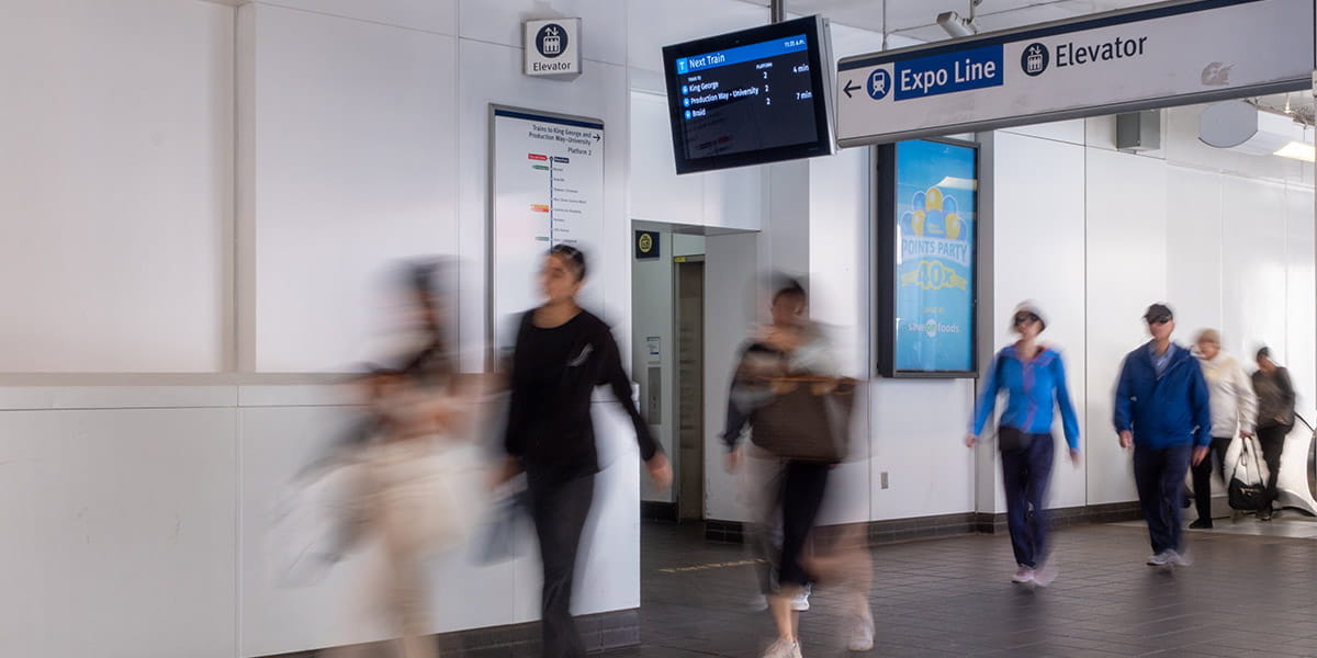 Commuters walking through the Waterfront SkyTrain station with signs for the Expo Line and an elevator