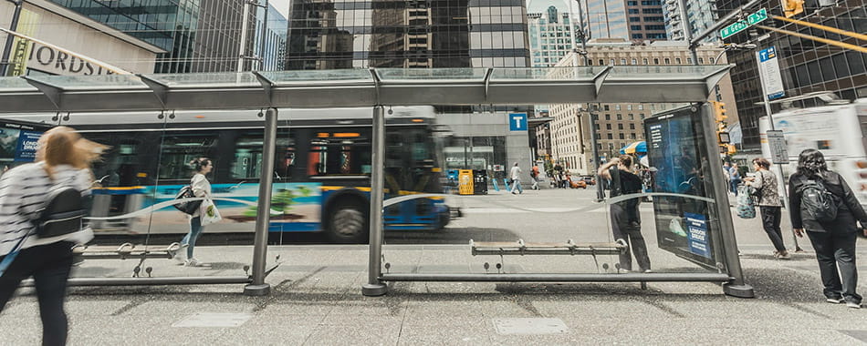 People walking around a bus shelter stop in the middle of downtown Vancouver