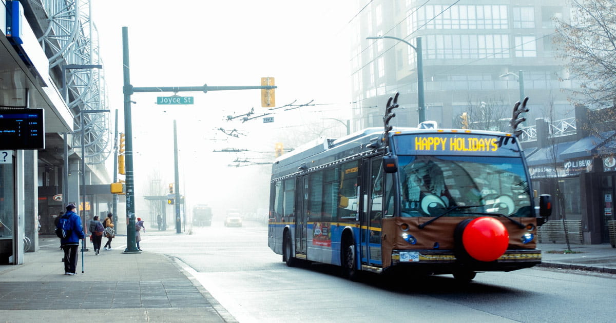 Reindeer Bus driving by Joyce—Collingwood Station and showing Happy Holidays on the destination sign.