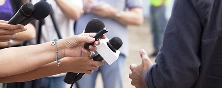 A couple of microphones pointing towards a public speaker